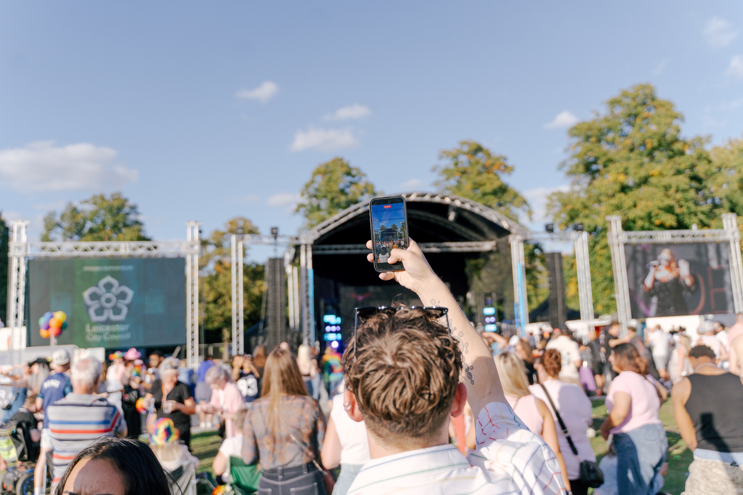 Festivalgoer filming the Leicester Pride 2026 stage on a phone